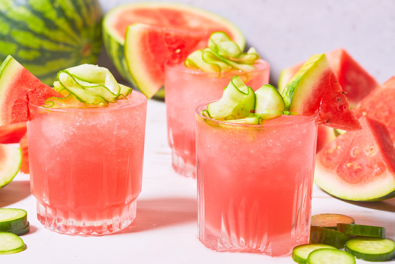 Trader Joe's Watermelon Cucumber Cooler; shown in several glasses, blended with ice and topped with a triangle of fresh watermelon and cucumber ribbons